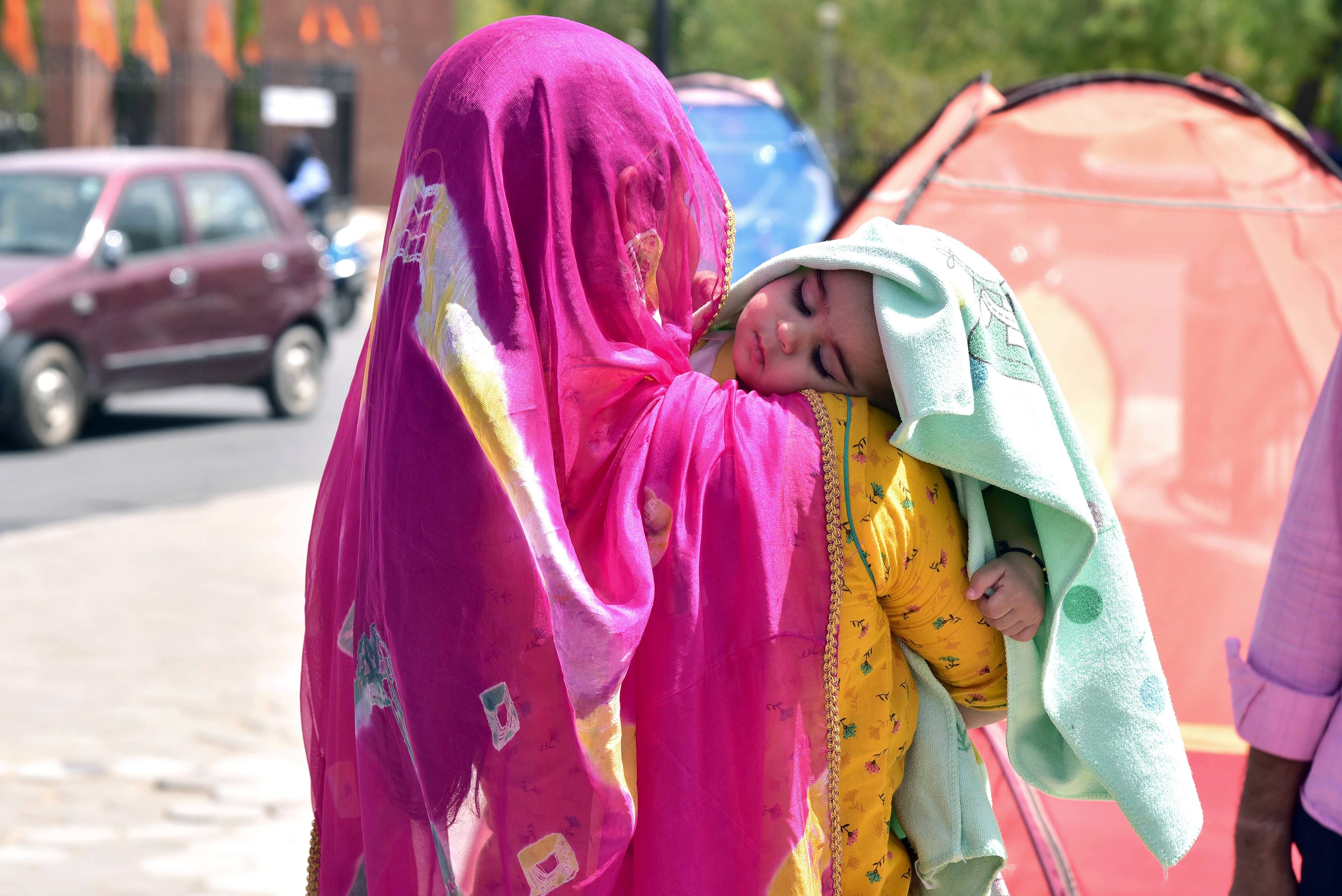 Bikaner, Mar 30 (ANI): A mother covers her child's head with a cloth on a hot summer day, in Bikaner on Wednesday. (ANI Photo)