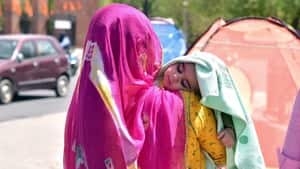 Bikaner, Mar 30 (ANI): A mother covers her child's head with a cloth on a hot summer day, in Bikaner on Wednesday. (ANI Photo)