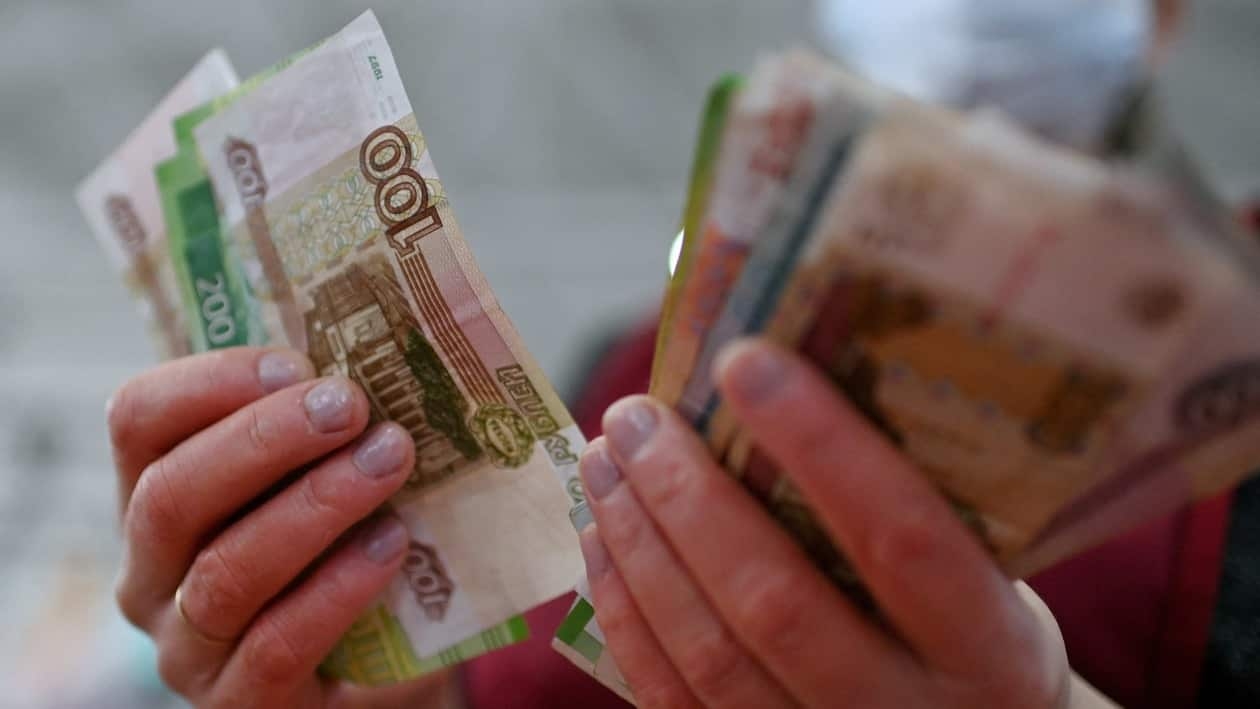 FILE PHOTO: A vendor counts Russian rouble banknotes at a market in Omsk, Russia February 18, 2022. REUTERS/Alexey Malgavko/File Photo