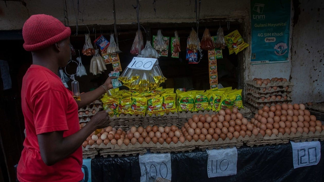 A man buys a sachet of cooking oil from a vendor at Arae 23 market in Lilongwe, Malawi, March 16, 2022. - From airlines in Nigeria to shoppers in Malawi, Africans are feeling the impact of the Ukraine crisis in wrenching increases in the price of fuel, grain and fertiliser. (Photo by Amos Gumulira / AFP)