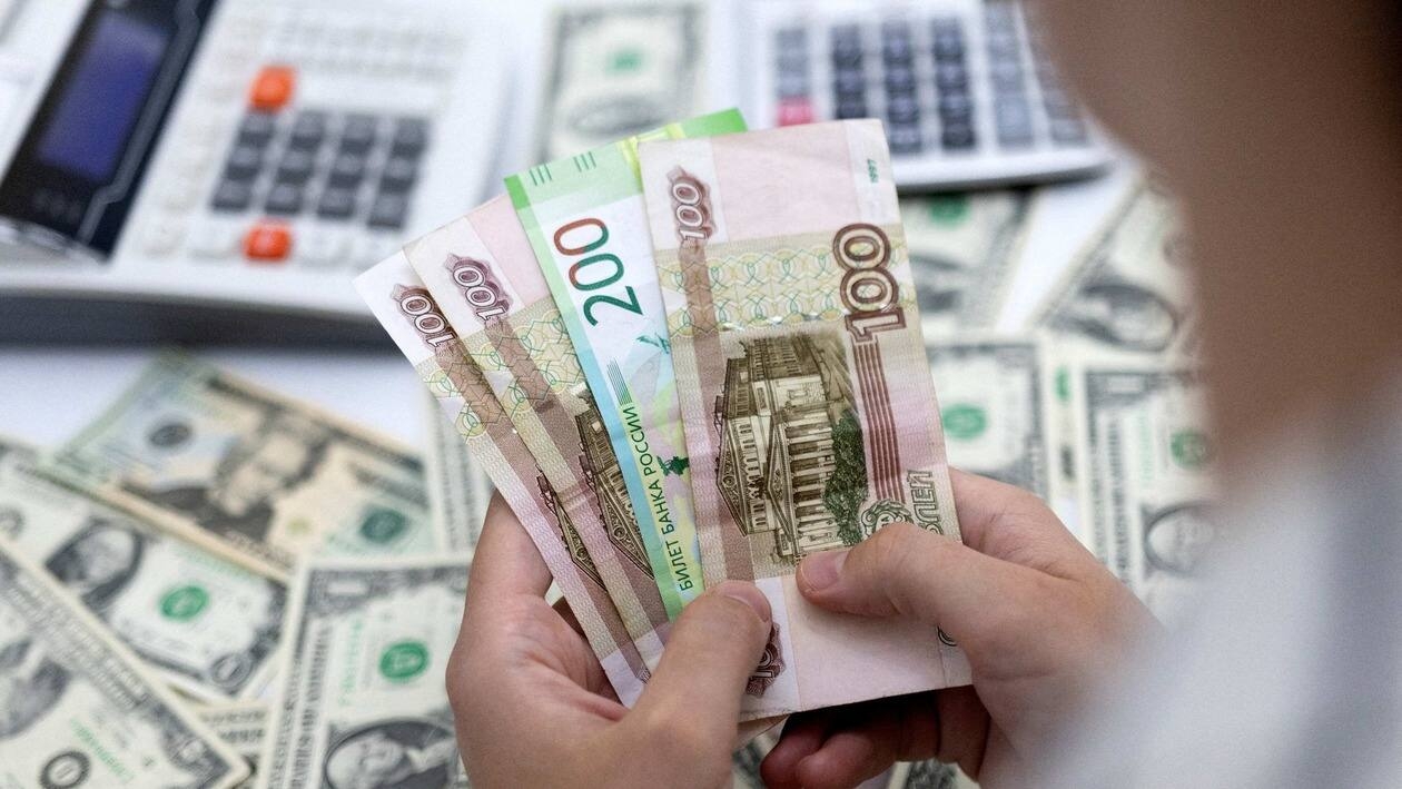 FILE PHOTO: A woman holds Russian Roubles in front of U.S. Dollar banknotes in this illustration taken May 30, 2022. REUTERS/Dado Ruvic/Illustration/File Photo