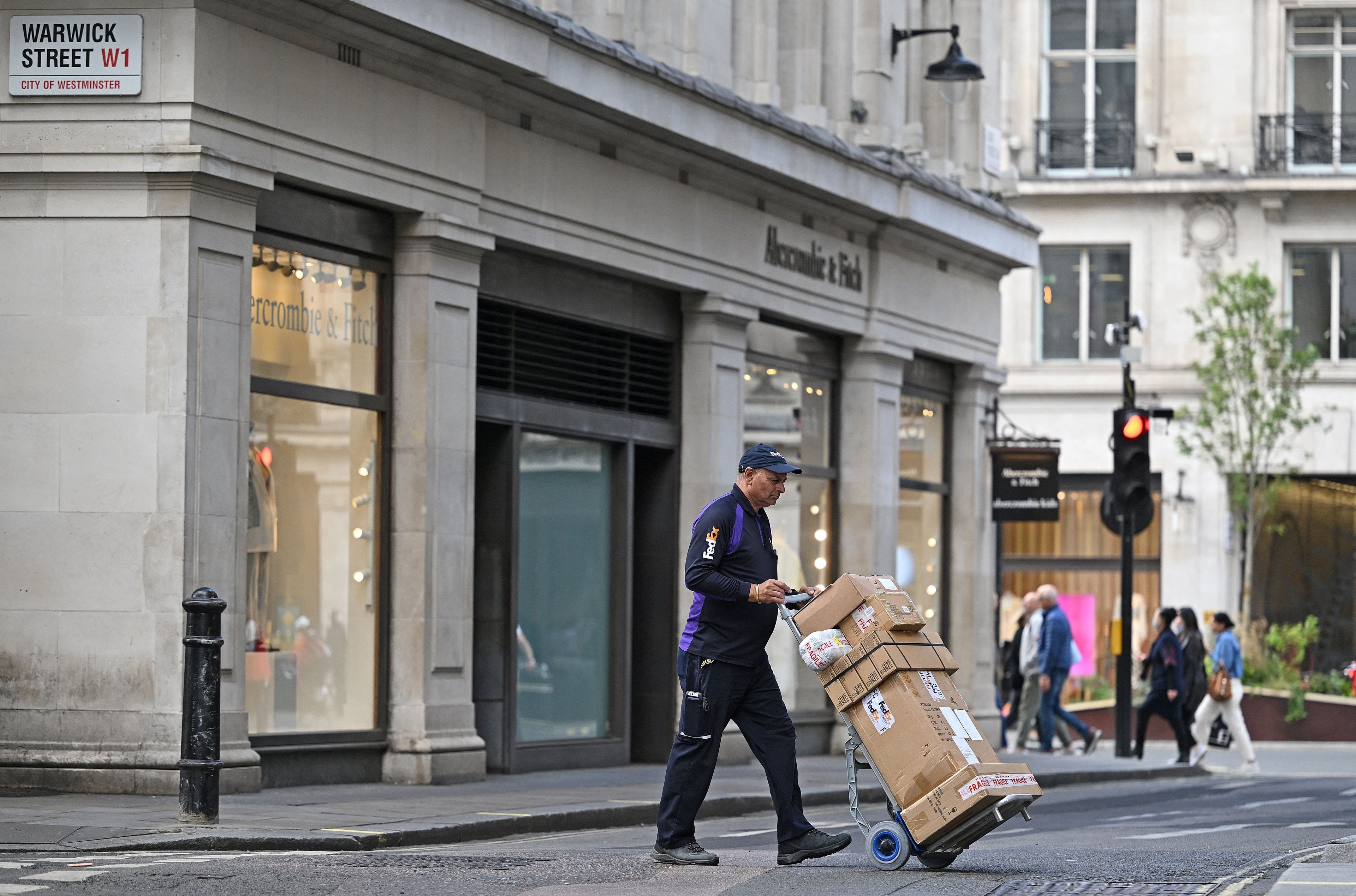 A Fedex delivery courier pushes parcels on a trolley in London on May 12, 2022. - Britain's economy shrank in March on fallout from soaring inflation, increasing the prospect of the country falling into recession. Official first-quarter data on Thursday showed that following solid output in January, the UK economy posted zero growth the following month and contracted by 0.1 percent in March. (Photo by JUSTIN TALLIS / AFP)