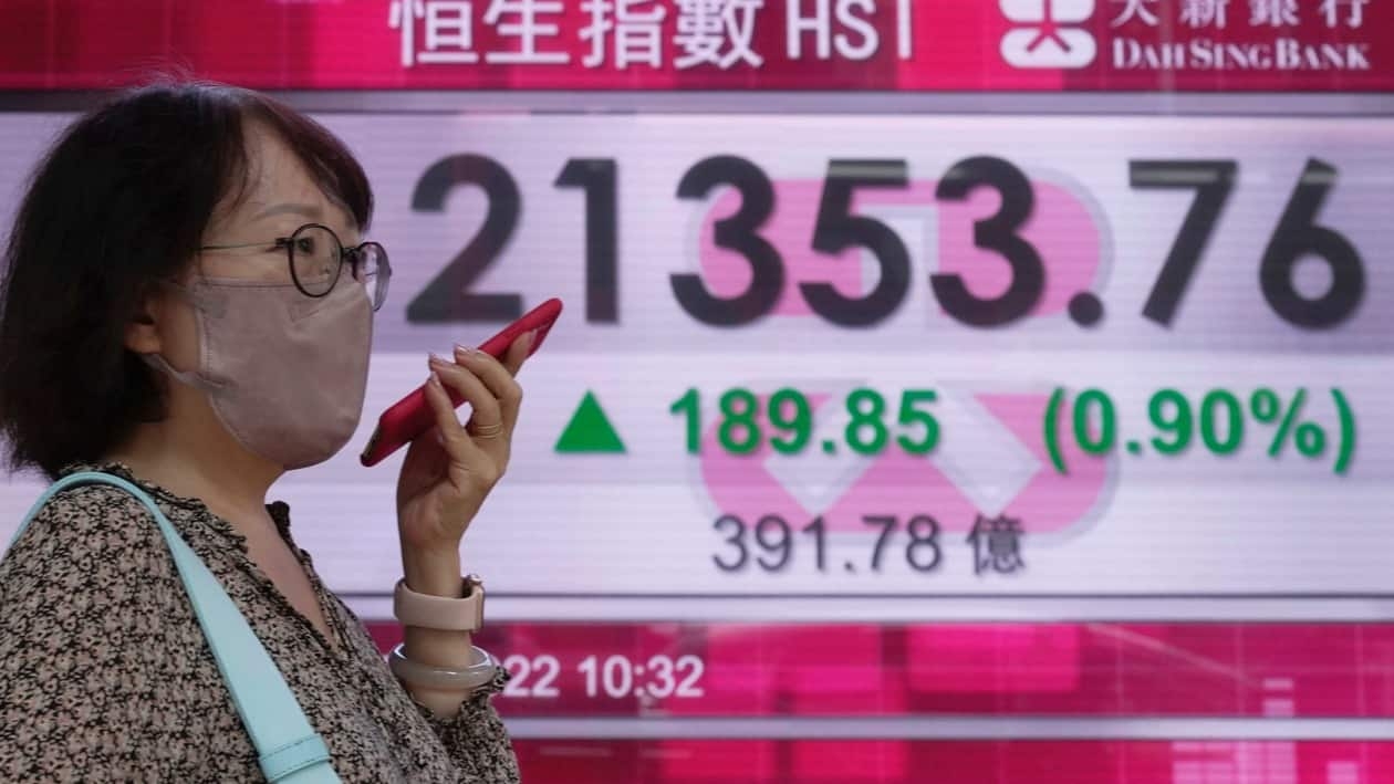 A woman wearing a face mask walks past a bank's electronic board showing the Hong Kong share index in Hong Kong, Tuesday, June 21, 2022. Asian stocks rebounded Tuesday as Wall Street futures moved higher while U.S. markets were closed for a holiday. (AP Photo/Kin Cheung)