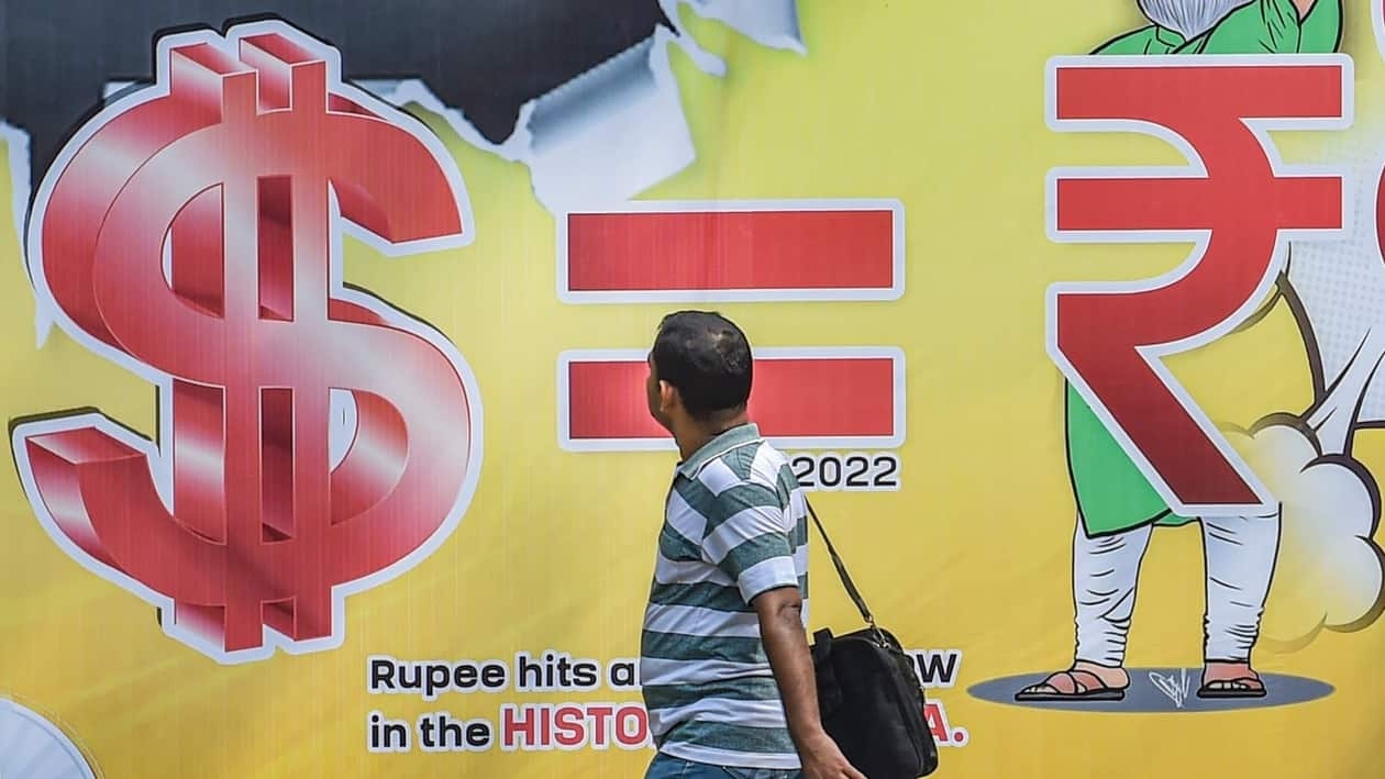 New Delhi: A man walks past a hoarding, depicting the Indian rupee's depreciation against the US currency, put up by Indian Youth Congress, in New Delhi, Saturday, July 16, 2022. The rupee has hit an all-time low of  <span class='webrupee'>₹</span>80 against a dollar. (PTI Photo/Manvender Vashist Lav)  (PTI07_16_2022_000024B)