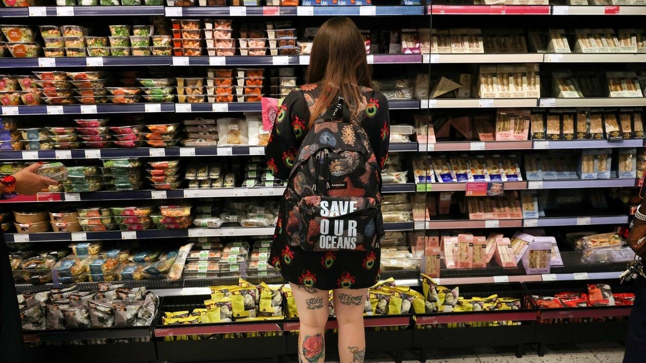 A person wearing a backpack with the slogan SAVE OUR OCEANS, looks at food goods in a shop as UK inflation heads towards 10% in London, Britain, June 16, 2022. REUTERS/Kevin Coombs