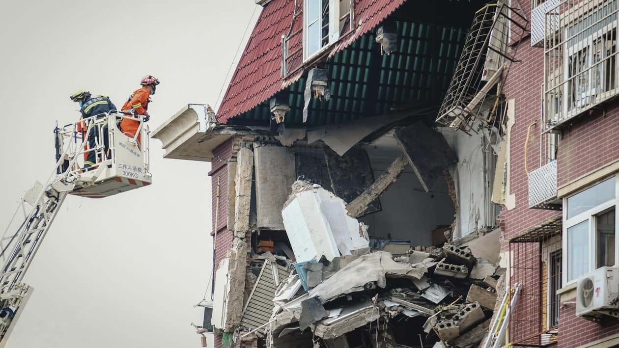 A fireman looks into the partially collapsed section of a building in China's Tianjin Municipality Tuesday, July 19, 2022. A gas explosion left some missing and others injured. (Chinatopix Via AP) CHINA OUT