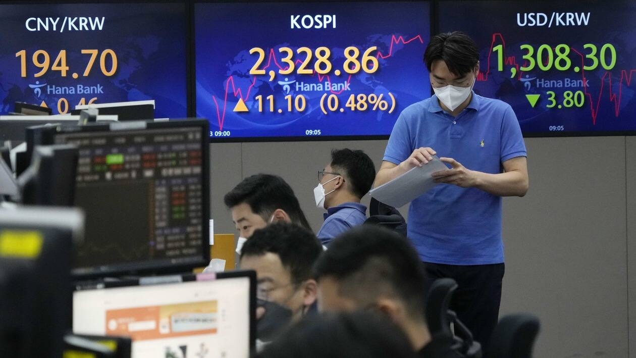 A currency trader passes by screens showing the Korea Composite Stock Price Index (KOSPI), center, and the exchange rate of South Korean won against the U.S. dollar, right, at the foreign exchange dealing room of the KEB Hana Bank headquarters in Seoul, South Korea, Wednesday, July 13, 2022. Asian stock markets rose Wednesday as investors waited for U.S. inflation data some worry might lead to more interest rate hikes.(AP Photo/Ahn Young-joon)