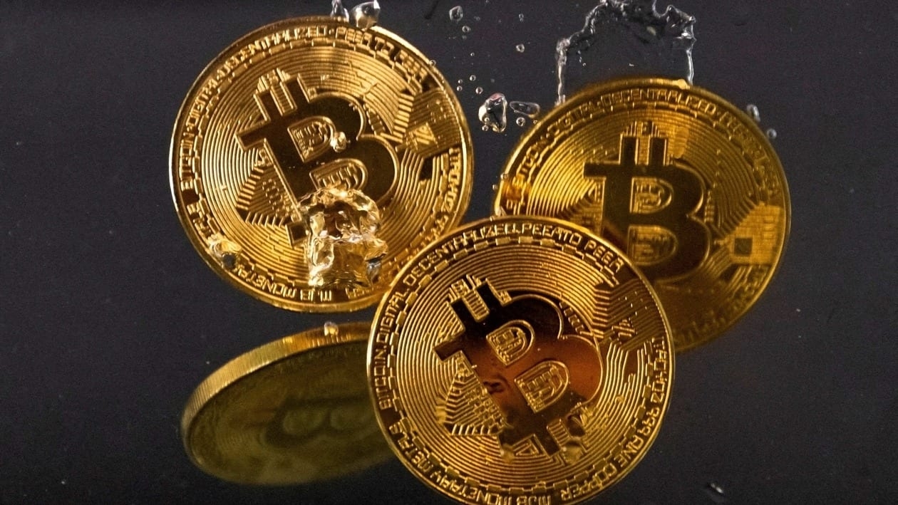 Souvenir tokens representing cryptocurrency bitcoin plunge into water&nbsp;