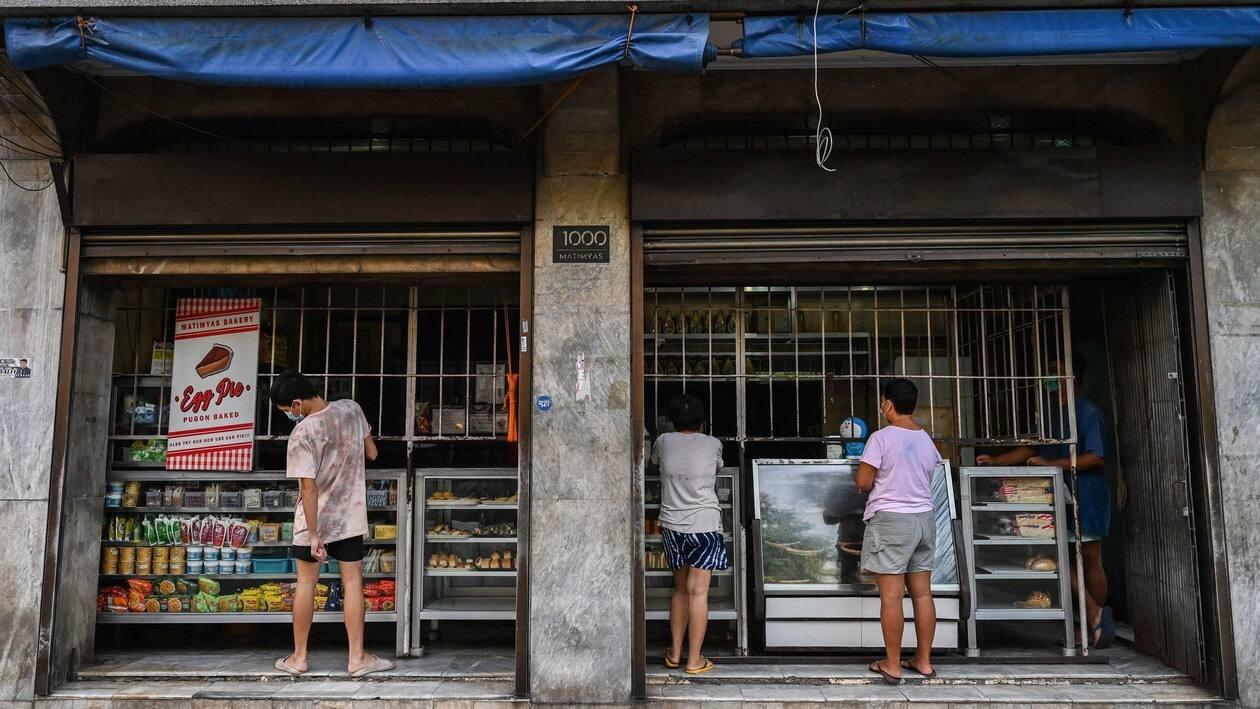 In this photo taken on July 20, 2022, people shop at a bakery that sells the popular breakfast roll 'pandesal' in Manila. - As the war in Ukraine pushes up wheat prices and a weaker peso raises the cost of imported edible oil, many Philippine bakers are shrinking the size of a popular breakfast roll to cope with higher inflation. (Photo by JAM STA ROSA / AFP) / To go with AFP story Philippines-economy-inflation, FOCUS by Mikhail FLORES