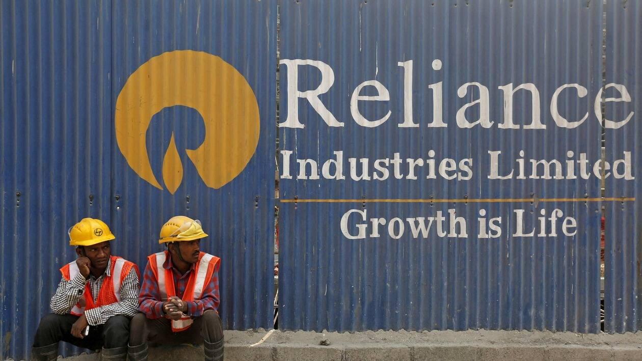 FILE PHOTO: Labourers rest in front of an advertisement of Reliance Industries Limited at a construction site in Mumbai, India, March 2, 2016. REUTERS/Shailesh Andrade/File Photo