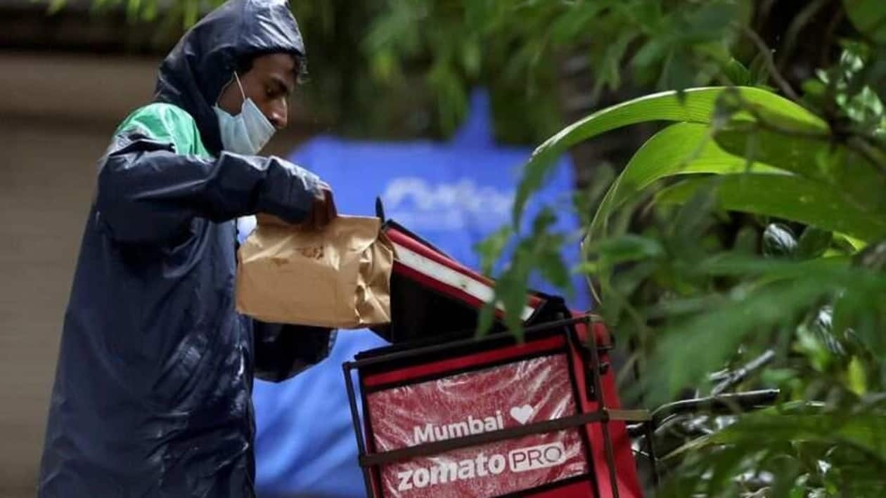 FILE PHOTO: A delivery worker of Zomato, an Indian food-delivery startup, picks a food package from his bag to deliver it to a customer in Mumbai, India, July 13, 2021. REUTERS/Francis Mascarenhas