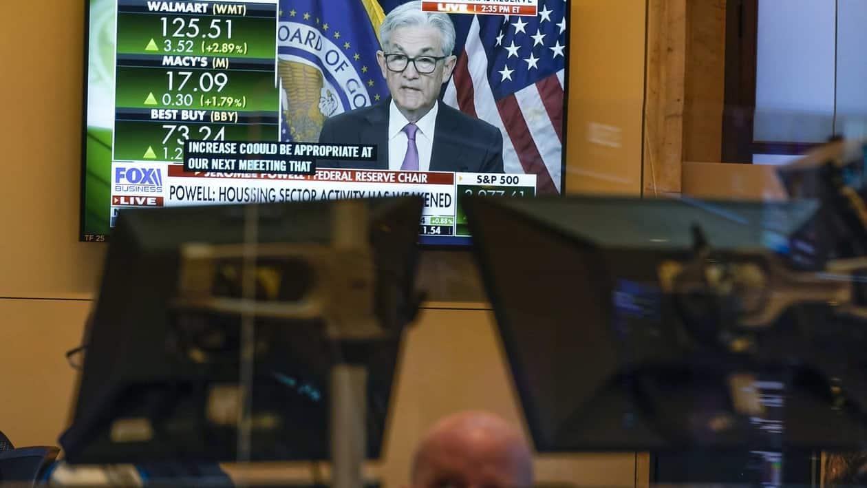 As traders work and watch, a news conference held by Federal Reserve Chair Jerome Powell is displayed at the New York Stock Exchange in New York, Wednesday, July 27, 2022. Stocks on Wall Street are solidly higher in afternoon trading Wednesday after the Federal Reserve raised its key interest rate by a widely expected three-quarters of a point as the central bank ratchets up its campaign to quell surging inflation. (AP Photo/Seth Wenig)