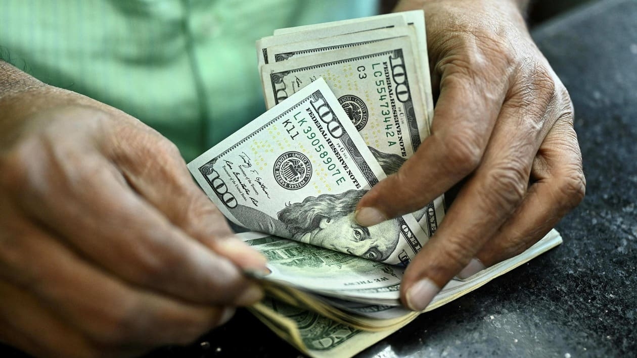 A man counts US dollars in a money exchange shop in Dhaka on July 28, 2022. (Photo by Munir uz zaman / AFP)
