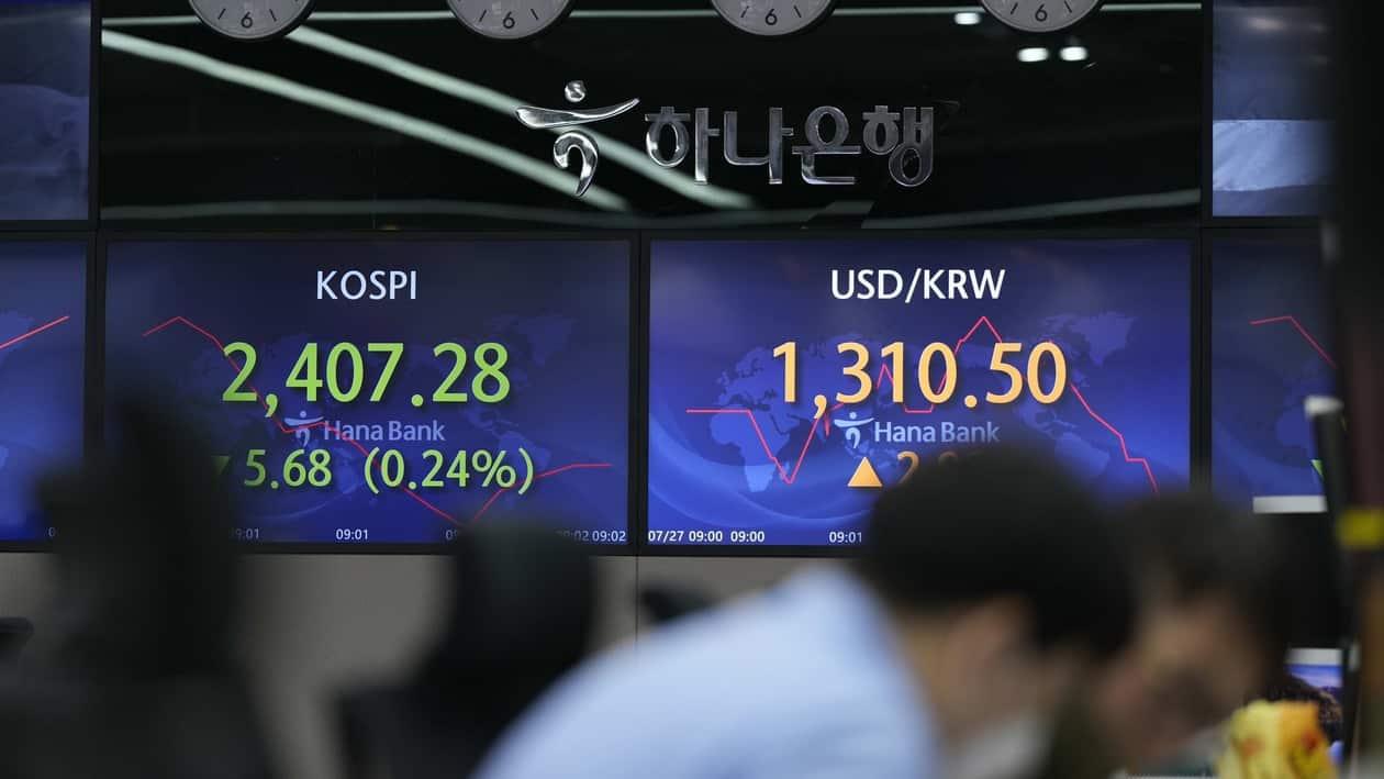 A currency trader talks near the screens showing the Korea Composite Stock Price Index (KOSPI), left, and the foreign exchange rate between U.S. dollar and South Korean won at a foreign exchange dealing room in Seoul, South Korea, Wednesday, July 27, 2022. Asian stock markets followed Wall Street lower Wednesday as traders prepared for a possible sharp interest rate hike from the Federal Reserve to cool inflation. (AP Photo/Lee Jin-man)