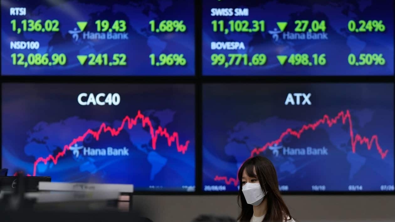 A currency trader walks near the screens at a foreign exchange dealing room in Seoul, South Korea, Wednesday, July 27, 2022. Asian stock markets followed Wall Street lower Wednesday as traders prepared for a possible sharp interest rate hike from the Federal Reserve to cool inflation. (AP Photo/Lee Jin-man)