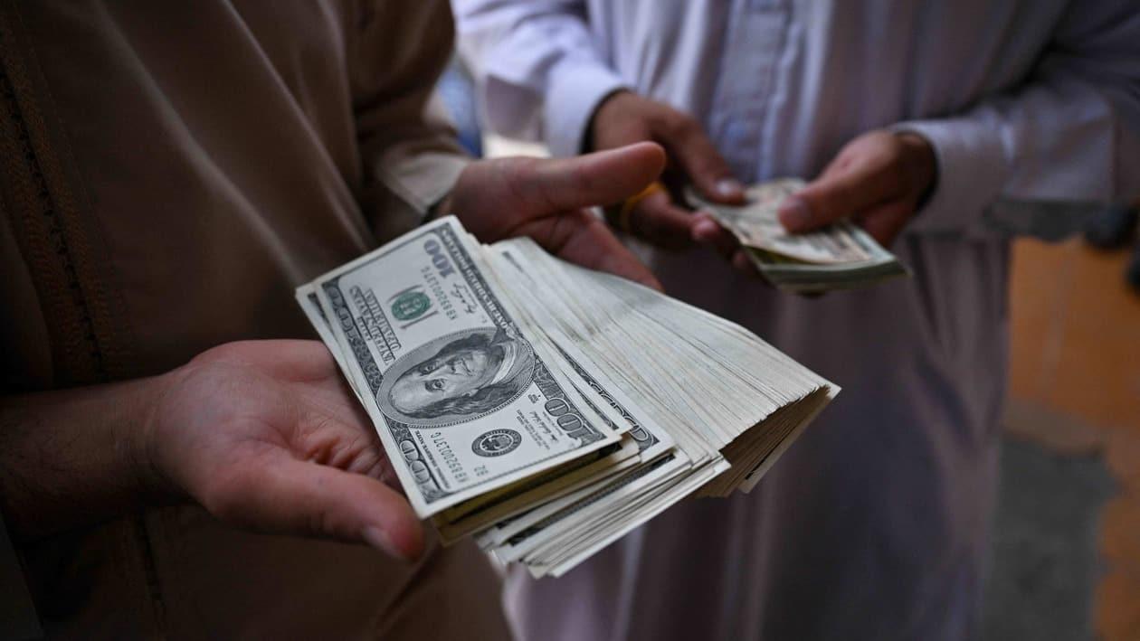 Currency traders show stacks of US dollars at the currency exchange centre in Herat city on August 4, 2022. (Photo by Lillian SUWANRUMPHA / AFP)