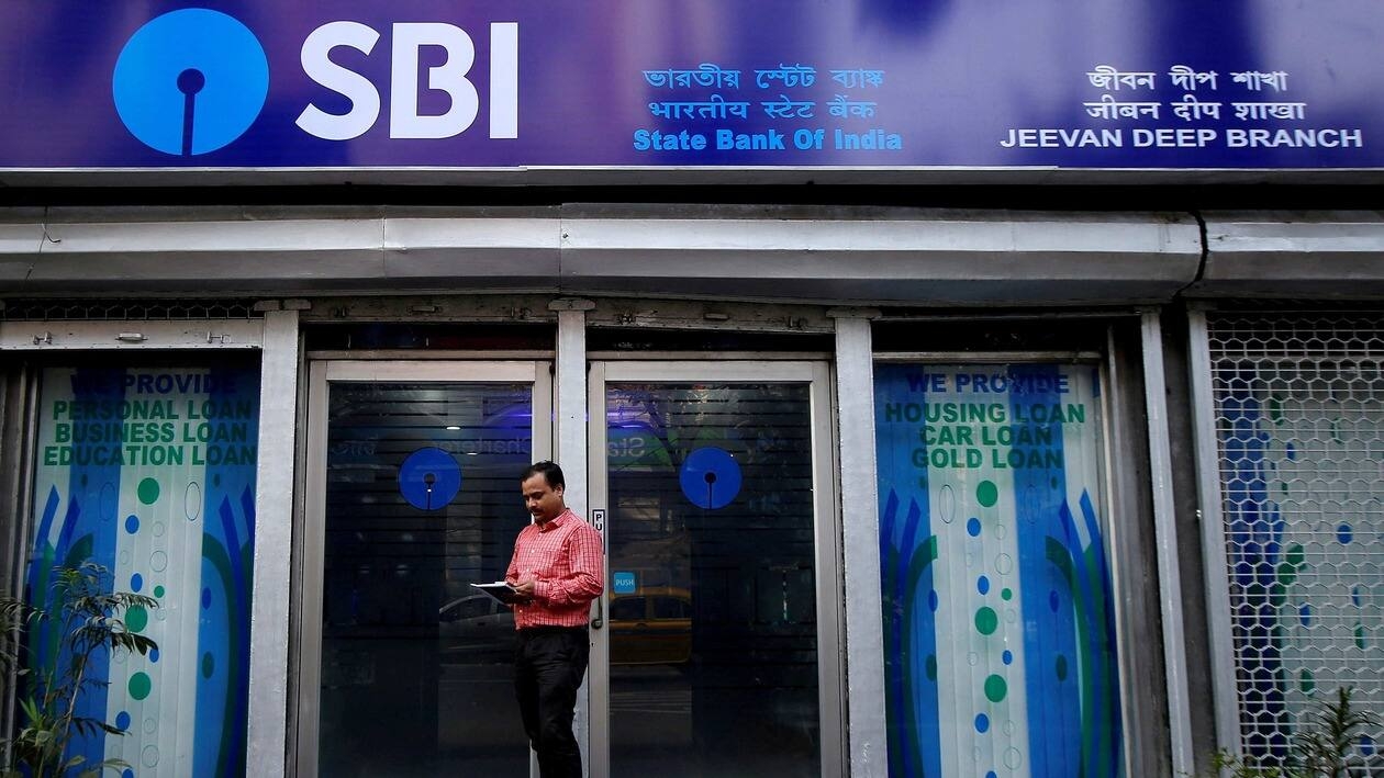 FILE PHOTO: A man checks his mobile phones in front of State Bank of India (SBI) branch in Kolkata, India, February 9, 2018. REUTERS/Rupak De Chowdhuri/File Photo