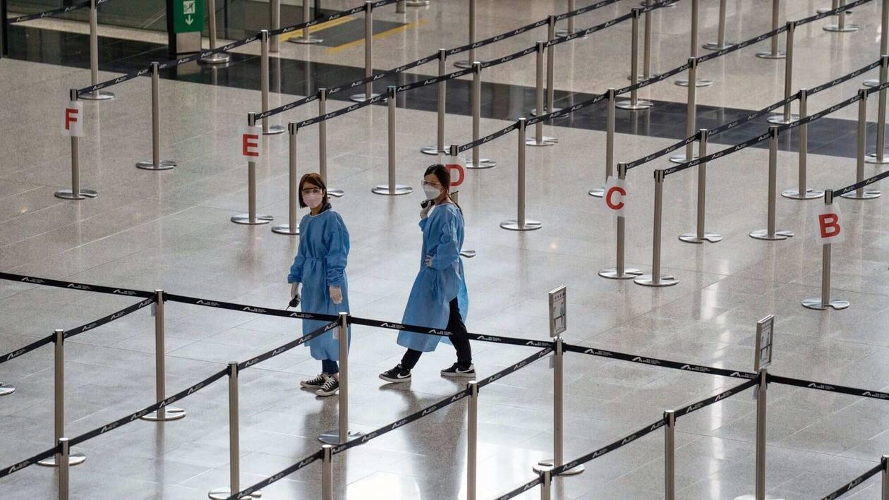 Workers in protective gear in an area for travelers heading to quarantine in the arrival hall at Hong Kong International Airport in Hong Kong, China, on Monday, Aug. 8, 2022. Hong Kong will reduce the period of time people entering the city must spend in hotel quarantine to three days from seven, a bolder-than-expected easing of its strict Covid-19 travel curbs, yet still leaving the Asian financial hub isolated in a world that�s mostly moved on from the pandemic. Photographer: Bertha Wang/Bloomberg