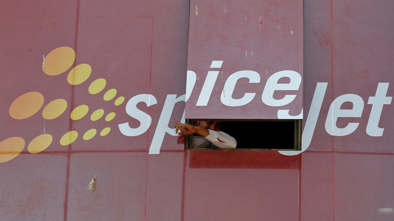 FILE PHOTO: A man looks out through a window with an advertisement of SpiceJet Airline, on a commercial building in the western Indian city of Ahmedabad February 14, 2014. REUTERS/Amit Dave (INDIA - Tags: TRANSPORT BUSINESS)/File Photo/File Photo