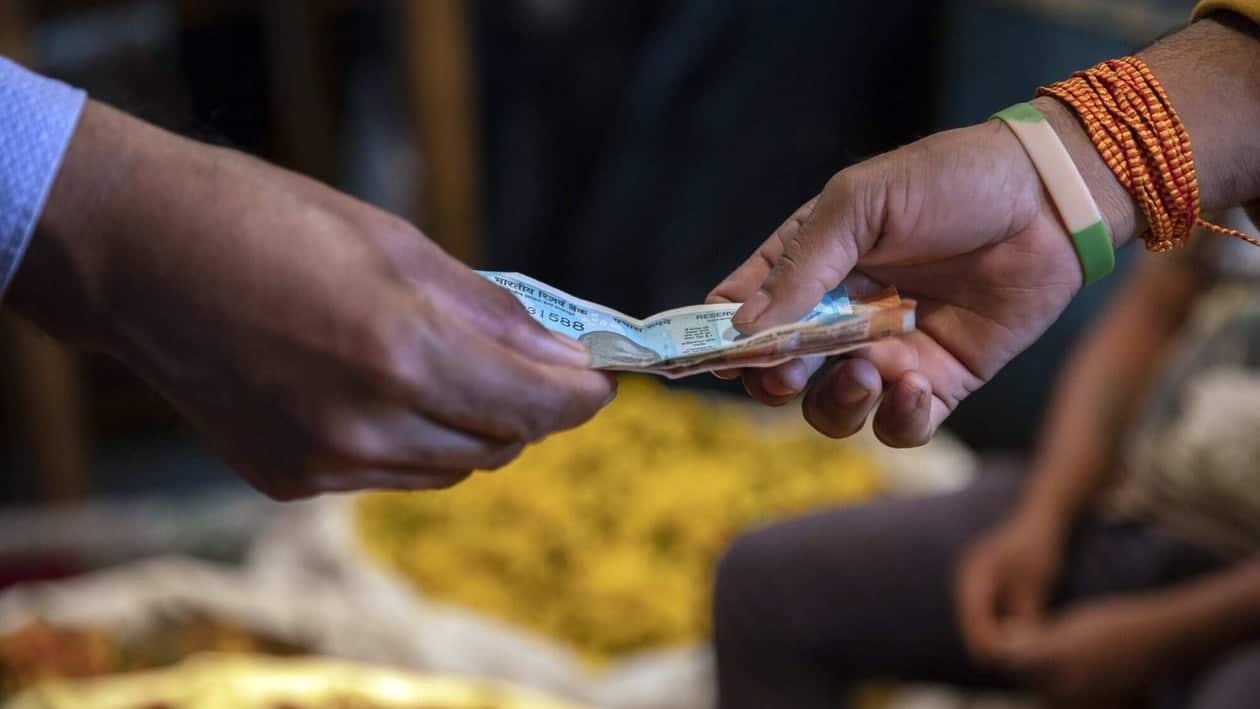 A customer and vendor exchange Indian rupee banknotes in Bengaluru, India, on Monday, Aug. 15, 2022. India�s�wholesale�price inflation due Aug. 16 would show price gains easing to 13.75% in July, from 15.18% the previous month, according to a separate survey as of last Friday. Photographer: Samyukta Lakshmi/Bloomberg