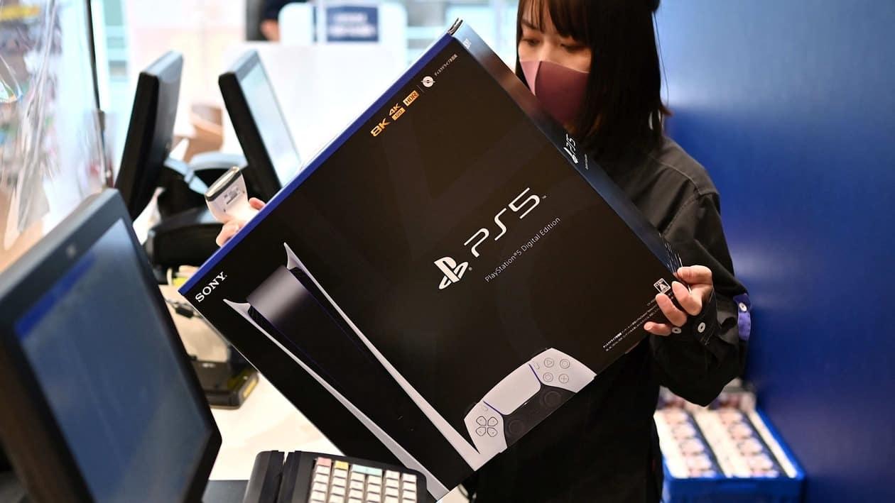 (FILES) This file photo taken on November 12, 2020 shows an employee handling a newly-purchased Sony PlayStation 5 gaming console for a customer on the first day of its launch, at an electronics shop in Kawasaki, Kanagawa prefecture. - The consoles made by Sony and Microsoft have been hard to buy since their November 2020 release, as has Nintendo's Switch, with supply chain issues exacerbated by lockdowns in China. (Photo by CHARLY TRIBALLEAU / AFP) / TO GO WITH AFP STORY JAPAN-GAMES-COMPUTERS-SEMICONDUCTORS,FOCUS BY MATHIAS CENA