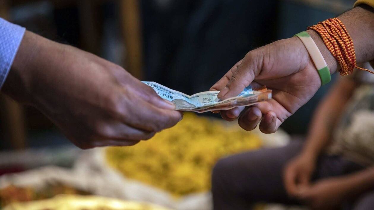 A customer and vendor exchange Indian rupee banknotes in Bengaluru, India, on Monday, Aug. 15, 2022. India�s�wholesale�price inflation due Aug. 16 would show price gains easing to 13.75% in July, from 15.18% the previous month, according to a separate survey as of last Friday. Photographer: Samyukta Lakshmi/Bloomberg