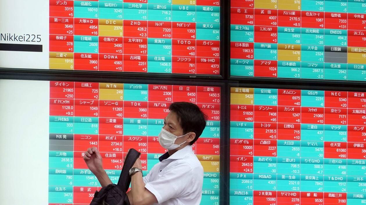 A man wearing a protective mask walks in front of an electronic stock board showing Japan's stock prices at a securities firm Friday, July 15, 2022, in Tokyo. Share prices were mixed in Asia on Friday after China reported its economy contracted by 2.6% in the last quarter as virus shutdowns kept businesses closed and people at home.(AP Photo/Eugene Hoshiko)