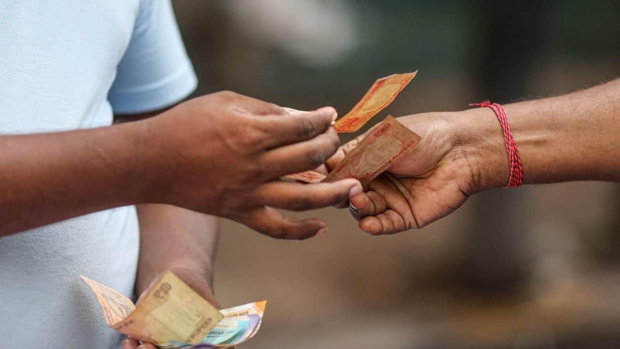 A shopper hands the Indian rupee banknotes to a roadside textile vendor in Mumbai, India, on Wednesday, July 20, 2022. The rupee slid to all-time low of 80.06 per dollar on Tuesday, and has lost 2.4% over the past month, the third-worst performing Asian currency over the period. Photographer: Dhiraj Singh/Bloomberg