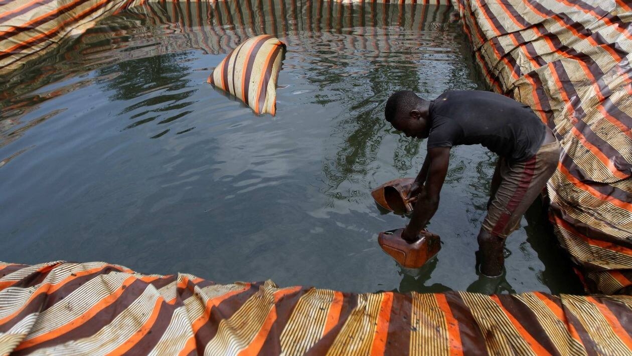FILE PHOTO: A man collects crude oil from a mini depot at an illegal oil refinery site near river Nun in Nigeria's oil state of Bayelsa November 27, 2012.  REUTERS/Akintunde Akinleye/File Photo