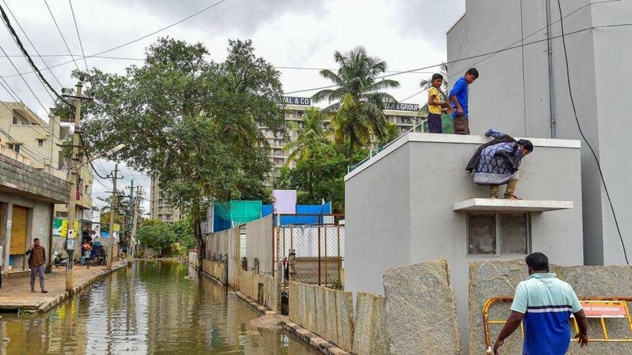Residents use barricade to enter and exit from their building in a flooded locality of Bellandur after heavy monsoon rains, in Bengaluru. (PTI)