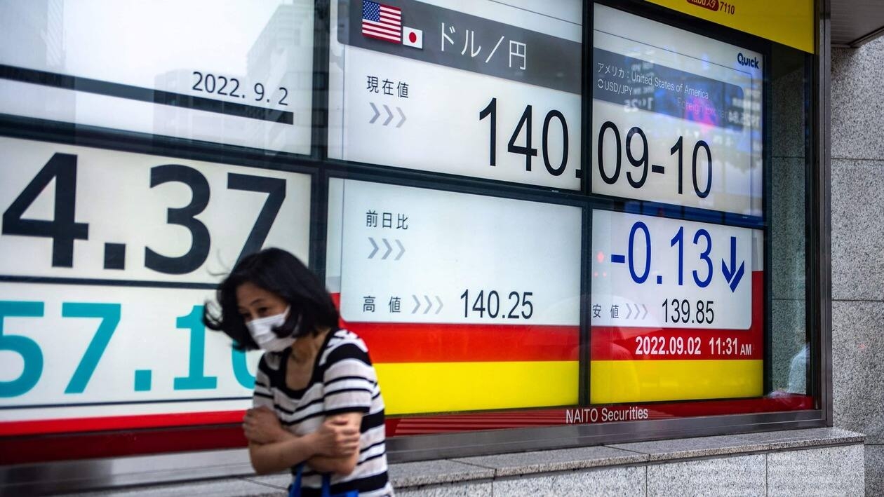 A pedestrian walks past an electronic quotation board displaying the rate of the Japanese yen against the US dollar in Tokyo on September 2, 2022. - The yen plunged to a new 24-year low against the dollar on September 1 as Japan sticks with its long-standing monetary easing policies in contrast to tightening by the US Federal Reserve. (Photo by Philip FONG / AFP)