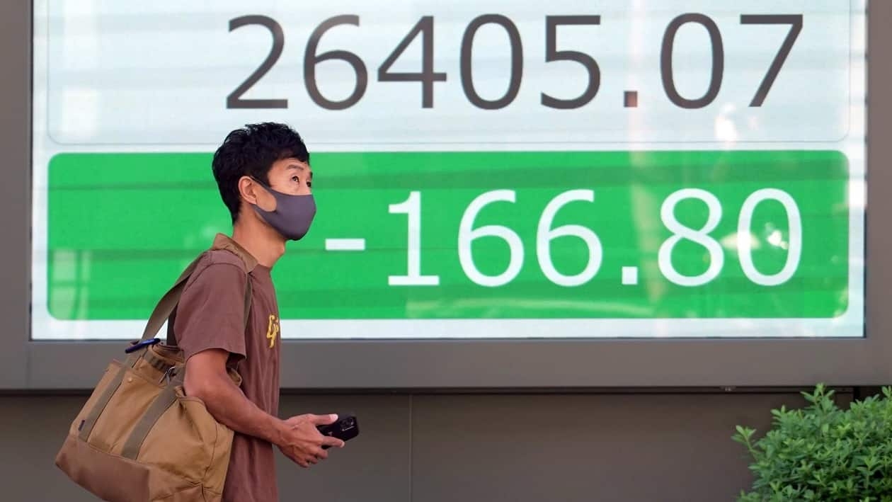 A person wearing a protective mask walks in front of an electronic stock board showing Japan's Nikkei 225 index at a securities firm Wednesday, Sept. 28, 2022, in Tokyo. Asian shares tumbled Wednesday after a wobbly day ended with mixed results on Wall Street as markets churn over the prospect of a possible recession. (AP Photo/Eugene Hoshiko)