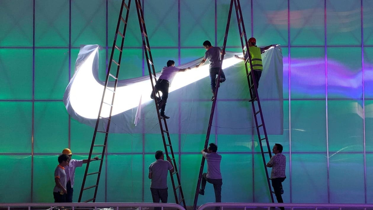 FILE PHOTO: Workers install a Nike logo lamp outside the Wukesong Arena in Beijing, China August 28, 2019. REUTERS/Tingshu Wang/File Photo