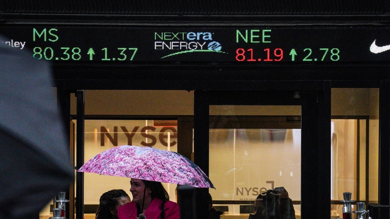 Umbrellas come out as people exit a the New York Stock Exchange doorway, where a financial ticker show the latest stock prices, Monday, Oct. 3, 2022, in New York. Wall Street rallied to its best day since late July as the S&P 500 rose 2.6%. (AP Photo/Bebeto Matthews)