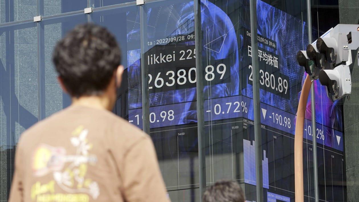 Pedestrians stand in front of an electronic stock board showing Japan's Nikkei 225 index at a securities firm Wednesday, Sept. 28, 2022, in Tokyo. Asian shares tumbled Wednesday after a wobbly day ended with mixed results on Wall Street as markets churn over the prospect of a possible recession. (AP Photo/Eugene Hoshiko)