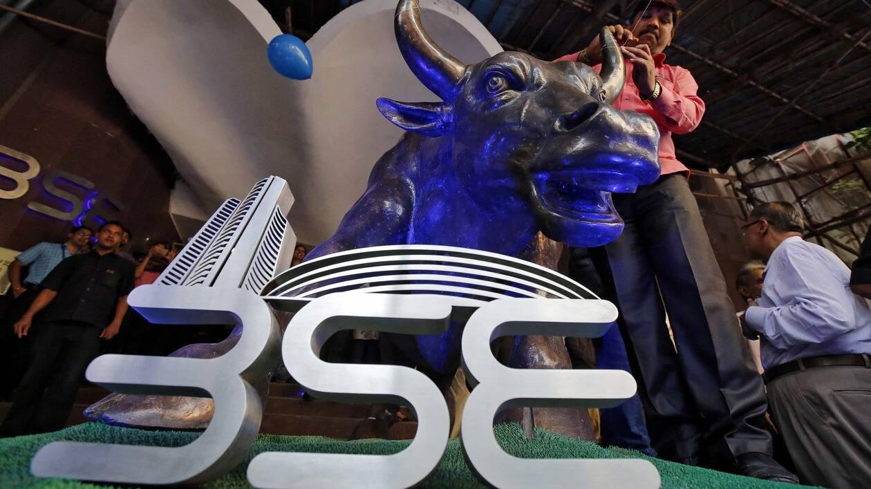 FILE PHOTO: A man ties a balloon to the horns of a bull statue at the entrance of the Bombay Stock Exchange (BSE) while celebrating the Sensex index rising to over 30,000, in Mumbai, India April 26, 2017. REUTERS/Shailesh Andrade/File Photo