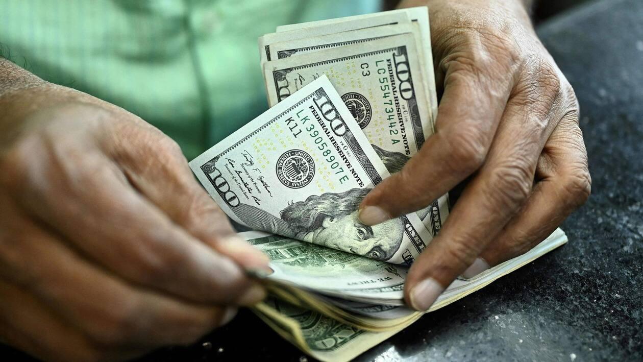 A man counts US dollars in a money exchange shop in Dhaka on July 28, 2022. (Photo by Munir uz zaman / AFP)