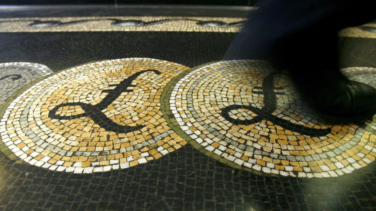 FILE PHOTO: An employee is seen walking over a mosaic of pound sterling symbols set in the floor of the front hall of the Bank of England in London, in this March 25, 2008 file photograph. REUTERS/Luke Macgregor//File Photo