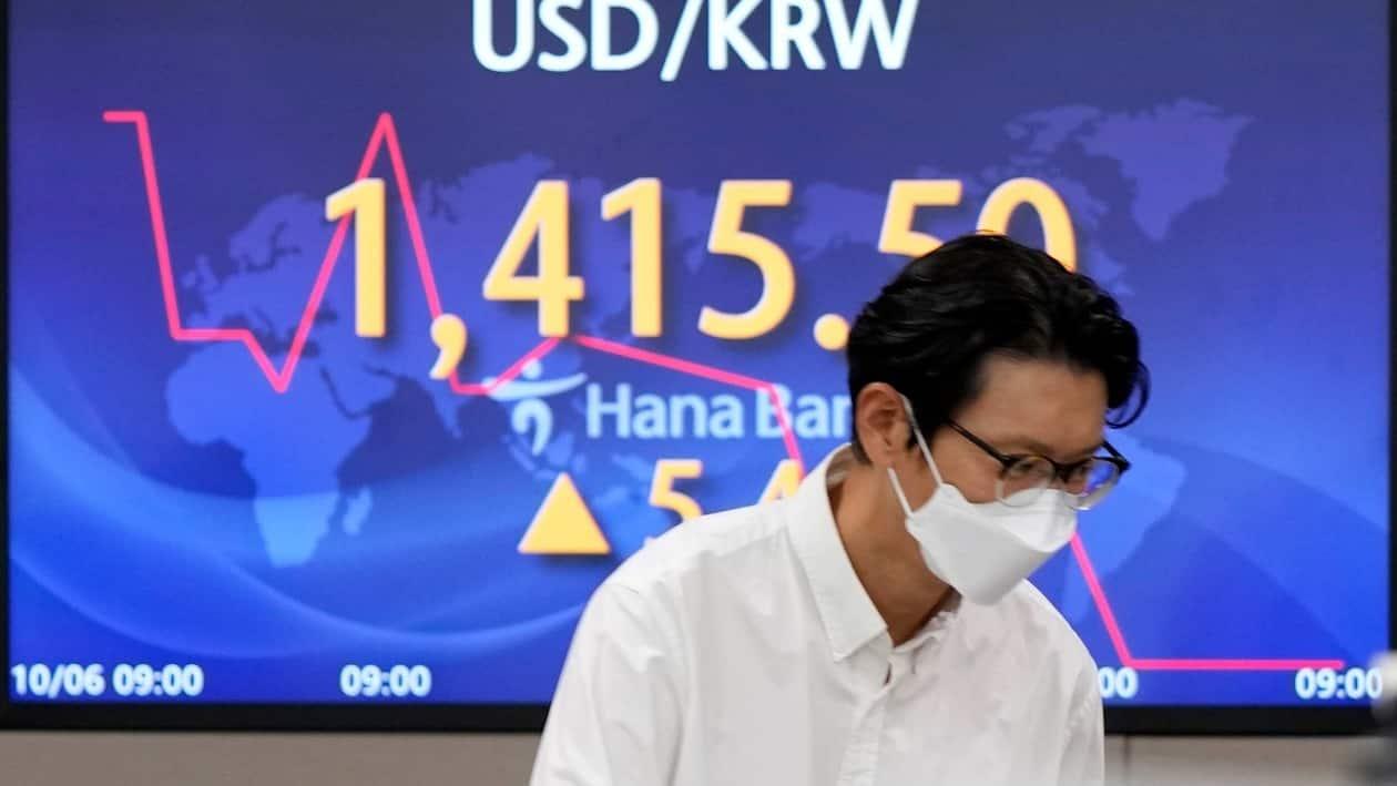 A currency trader walks by the screen showing the foreign exchange rate between U.S. dollar and South Korean won at a foreign exchange dealing room in Seoul, South Korea, Thursday, Oct. 6, 2022. Asian stocks were mixed Thursday after strong U.S. hiring dampened hopes the Federal Reserve might ease off plans for interest rate hikes and the OPEC group of oil exporters agreed to output cuts to shore up prices. (AP Photo/Lee Jin-man)