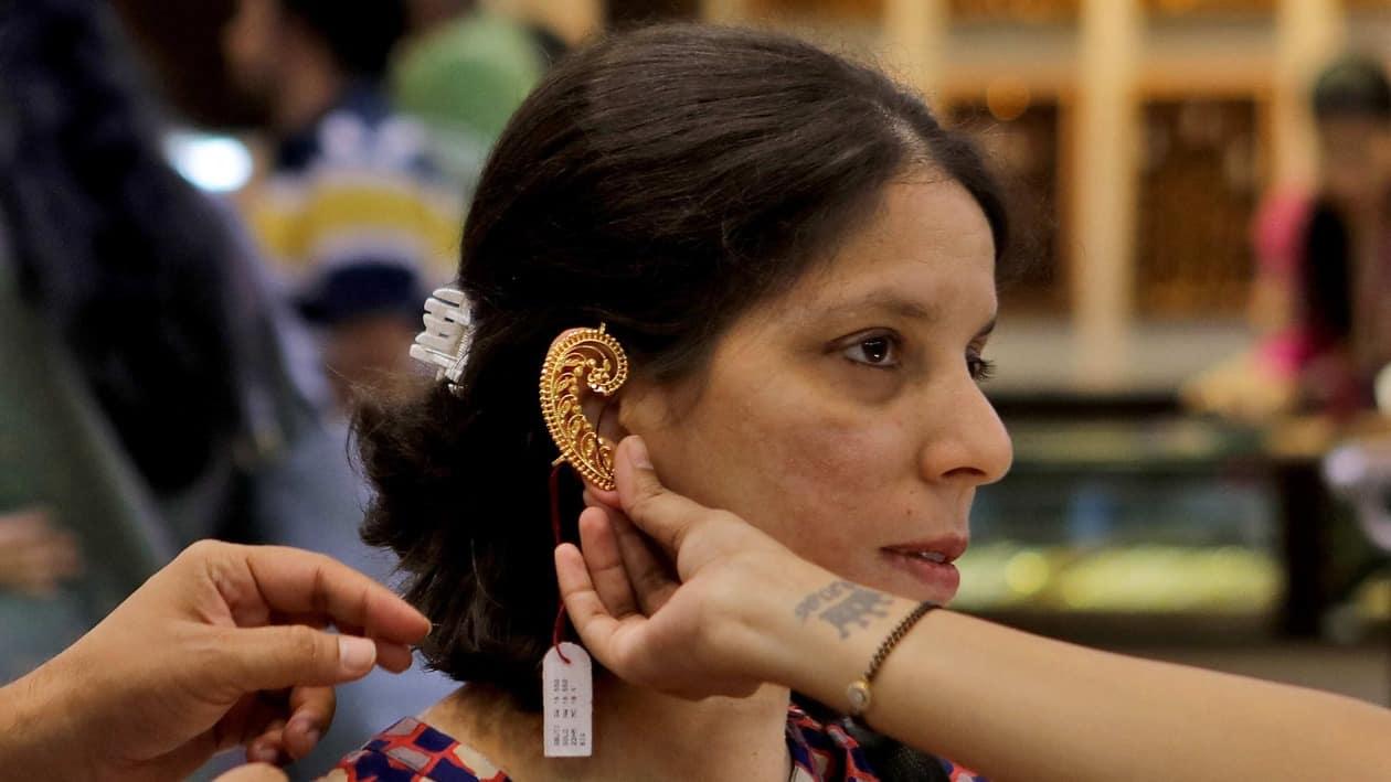 A woman tries on a gold ear ornament at a jewellery showroom during Dhanteras, a Hindu festival associated with Lakshmi, the goddess of wealth, in Mumbai, India, October 22, 2022. REUTERS/Niharika Kulkarni