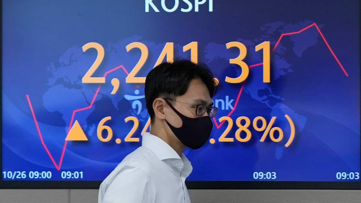 A currency trader walks near a screen showing the Korea Composite Stock Price Index (KOSPI) at a foreign exchange dealing room in Seoul, South Korea, Wednesday, Oct. 26, 2022. Asian stock markets followed Wall Street higher on Wednesday as hopes rose that the Federal Reserve might ease off plans for interest rate hikes and Britain installed its third prime minister this year. (AP Photo/Lee Jin-man)
