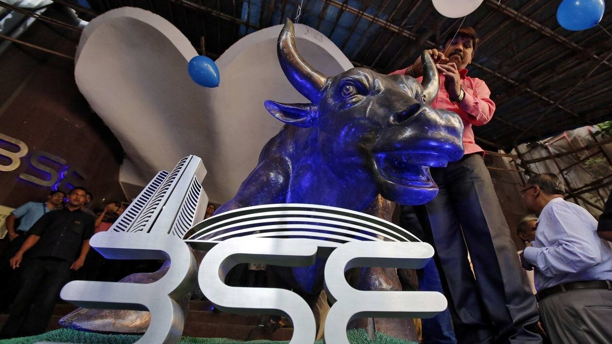 FILE PHOTO: A man ties a balloon to the horns of a bull statue at the entrance of the Bombay Stock Exchange (BSE) while celebrating the Sensex index rising to over 30,000, in Mumbai, India April 26, 2017. REUTERS/Shailesh Andrade/File Photo