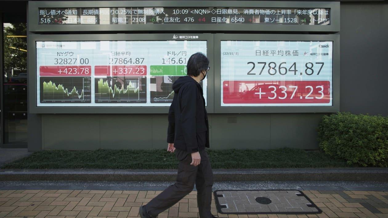 A man looks at Japan's Nikkei 225 index on monitors also showing the Japanese yen against the U.S. dollar, center, and the New York Dow index, far left, at a securities firm in Tokyo, Tuesday, Nov. 8, 2022. Asian stocks were mixed Tuesday ahead of the U.S. midterm elections with trading likely to stay bumpy in a week that brings new inflation data and other events that could shake markets. (AP Photo/Hiro Komae)