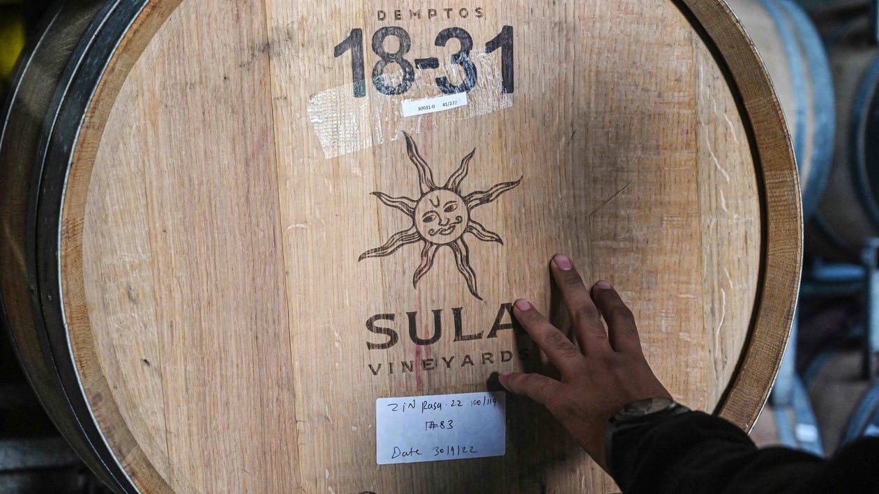 In this photograph taken on October 19, 2022, a visitor touches a wine barrel during a tour at the winery of Sula Vineyards  in Nashik. - India's largest winemaker Sula Vineyards is heading to the stock market, betting on the diversifying tastebuds of a booming urban middle class in a country that has long favoured heavy liquors. Wine makes up less than one percent of India's massive alcohol market, with spirits the overwhelming tipples of choice in the nation of 1.4 billion people. (Photo by Indranil MUKHERJEE / AFP) / TO GO WITH 'India-lifestyle-wine-economy-climate-agriculture', FOCUS by Glenda Kwek.