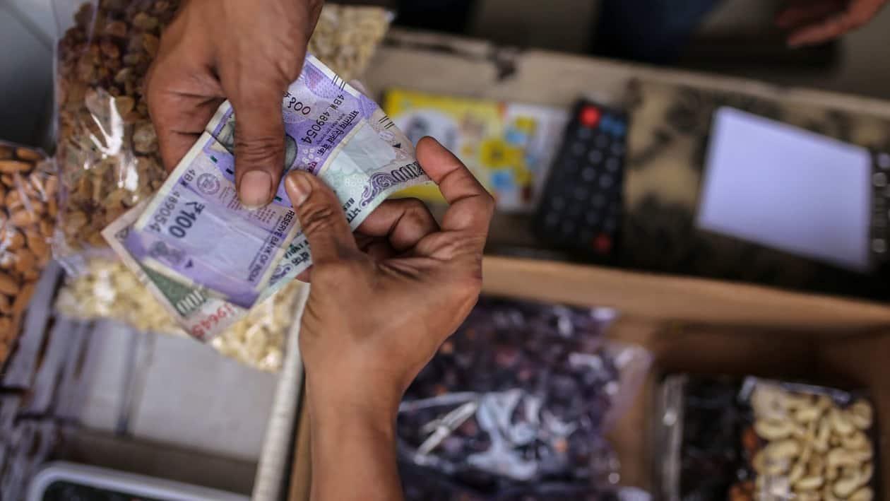 Customers holds rupee banknotes at a grocery store in Mumbai, India, on Saturday, Jan. 7, 2023. India is scheduled to release consumer price index (CPI) figures on Jan. 12. Photographer: Dhiraj Singh/Bloomberg