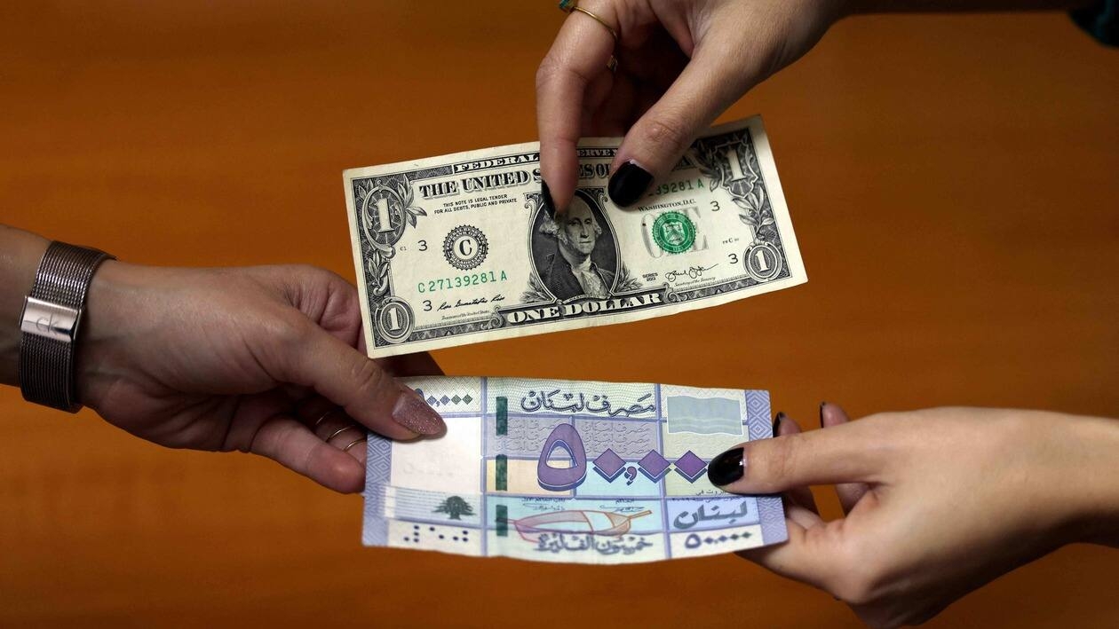 This picture shows two women exchanging a one US dollar bill against a fifty thousand Lebanese pound (lira) banknote, in the Lebanese capital Beirut, on January 19, 2023. - The Lebanese currency reached the psychological threshold of 50,000 pounds for one US dollar in the parallel market today, in the country in full economic collapse and where the deputies again failed to elect a president. (Photo by JOSEPH EID / AFP)