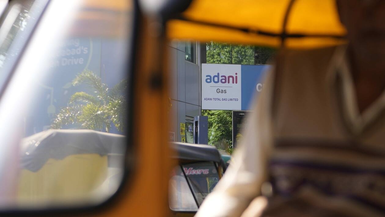 An autorickshaw driver waits for passengers in front of an Adani gas customer care centre in Ahmedabad, India, Feb. 2, 2023. Shares in Adani Enterprises tumbled 26% Thursday, while stock in six other Adani companies fell 5%-10%. Adani slid from being the world’s third richest man to the 13th as his fortune sank to $72 billion, according to Bloomberg’s Billionaire Index. (AP Photo/Ajit Solanki)