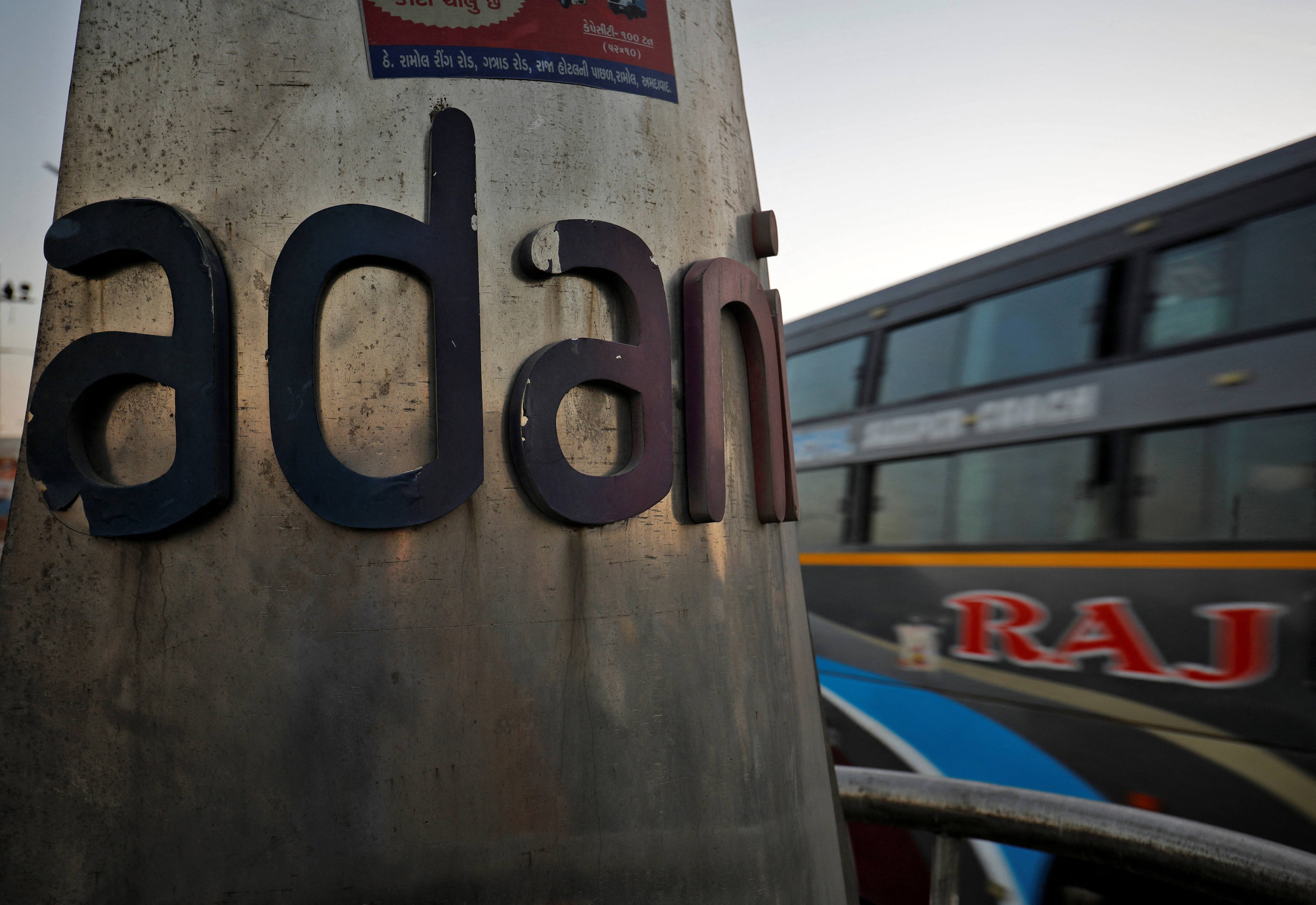 A passenger bus moves past the logo of the Adani Group installed at a roundabout on the ring road in Ahmedabad, India, February 2, 2023. REUTERS/Amit Dave