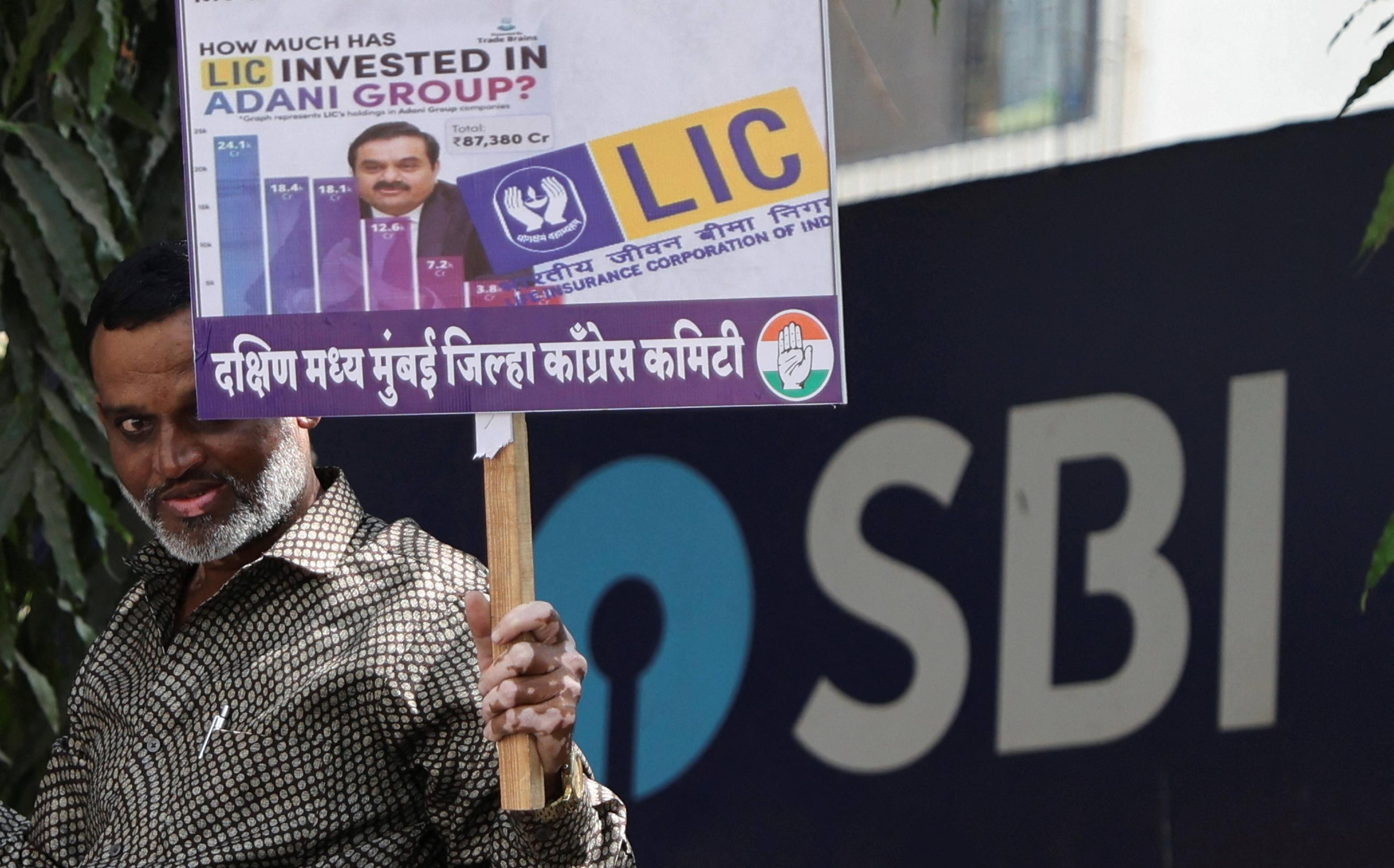 An activist of India's main opposition Congress party holds a placard, demanding a probe into the Adani Group, outside a State Bank of India branch in Mumbai, India, February 6, 2023. REUTERS/Francis Mascarenhas