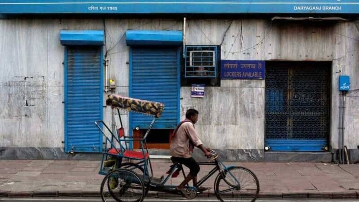 A rickshaw puller passes the Canara Bank branch in the old quarters of Delhi, India.